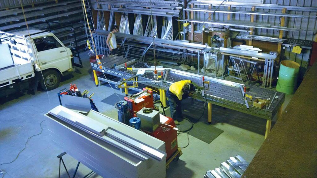 Fabricator welding an aluminium frame on a Demmeler 3D welding table in D&T Balustrade Systems' Illawarra workshop
