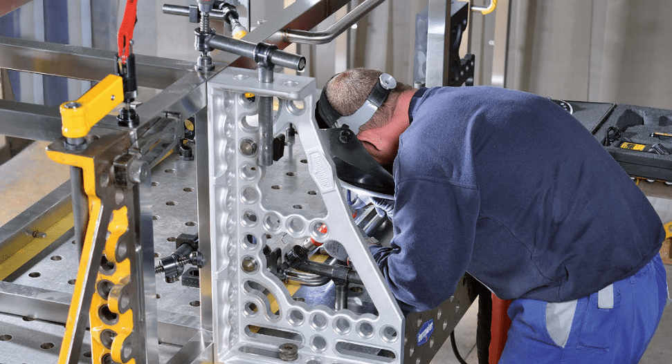 Worker welding precision components using a Demmeler modular fixturing system for accurate assembly