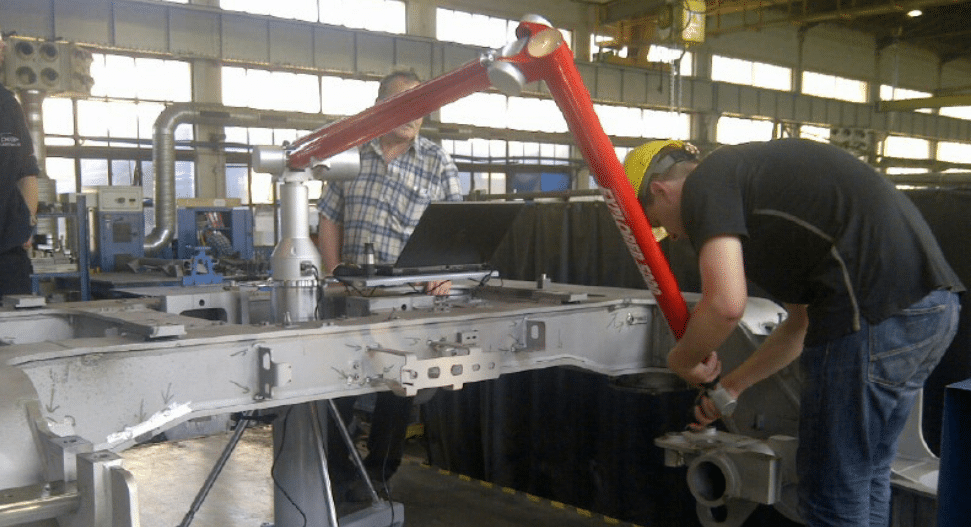 Engineer using a Tomelleri Explorer articulating arm on a large metal frame.