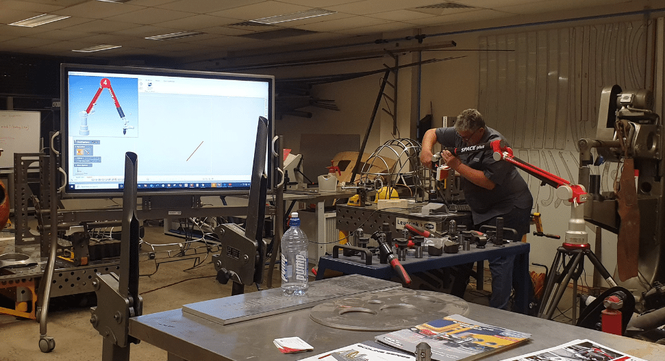 Technician Using A Portable Cmm Arm In A Metrology Lab To Measure And Inspect A Fabricated Component With Real Time 3d Measurement Software Displayed On Screen