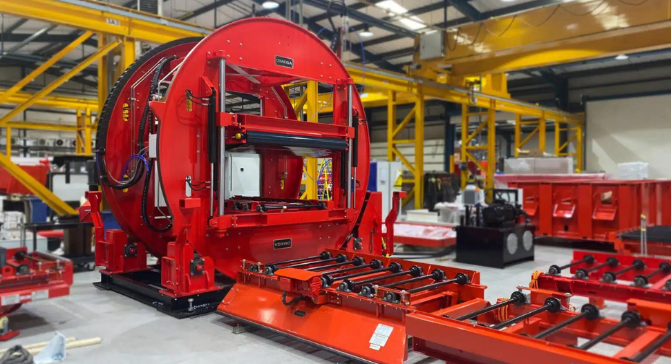 Omega Sinto mould handling machine in a modern foundry facility, featuring a large red circular mould system with integrated conveyor rollers and automated transfer equipment.
