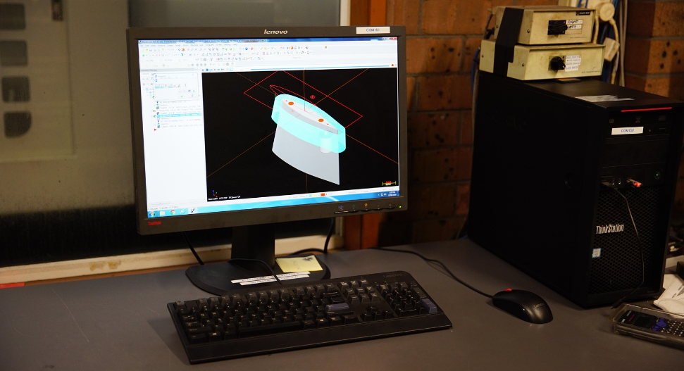 CAD/CAM programming workstation used for CNC toolpath generation, displaying a 3D solid model of a precision component ready for machining