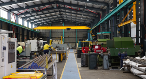 Full-service heavy industry machine shop floor with CNC and conventional machinery, overhead cranes and hi-vis workers demonstrating end-to-end engineering capability.