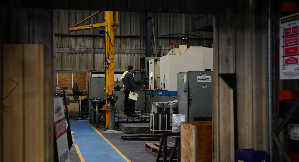 Two heavy industry engineers collaborating on CNC machining operations in a full-service engineering workshop