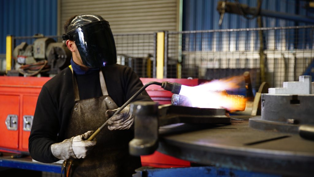 Leussink metal fabricator using a gas torch on a metal component in an Australian industrial workshop